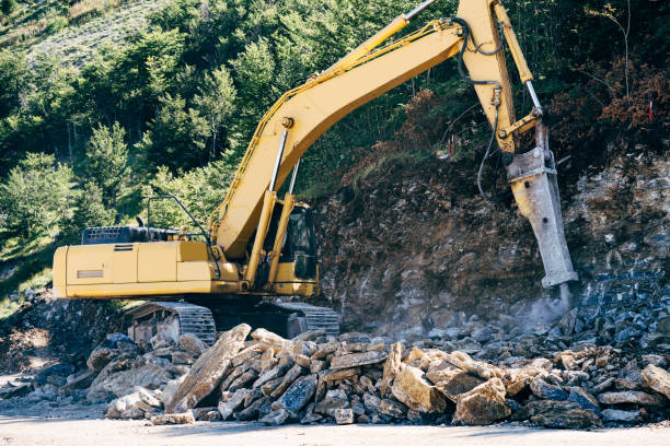 Yellow tracked tractor drills stones near the mountain. High quality photo